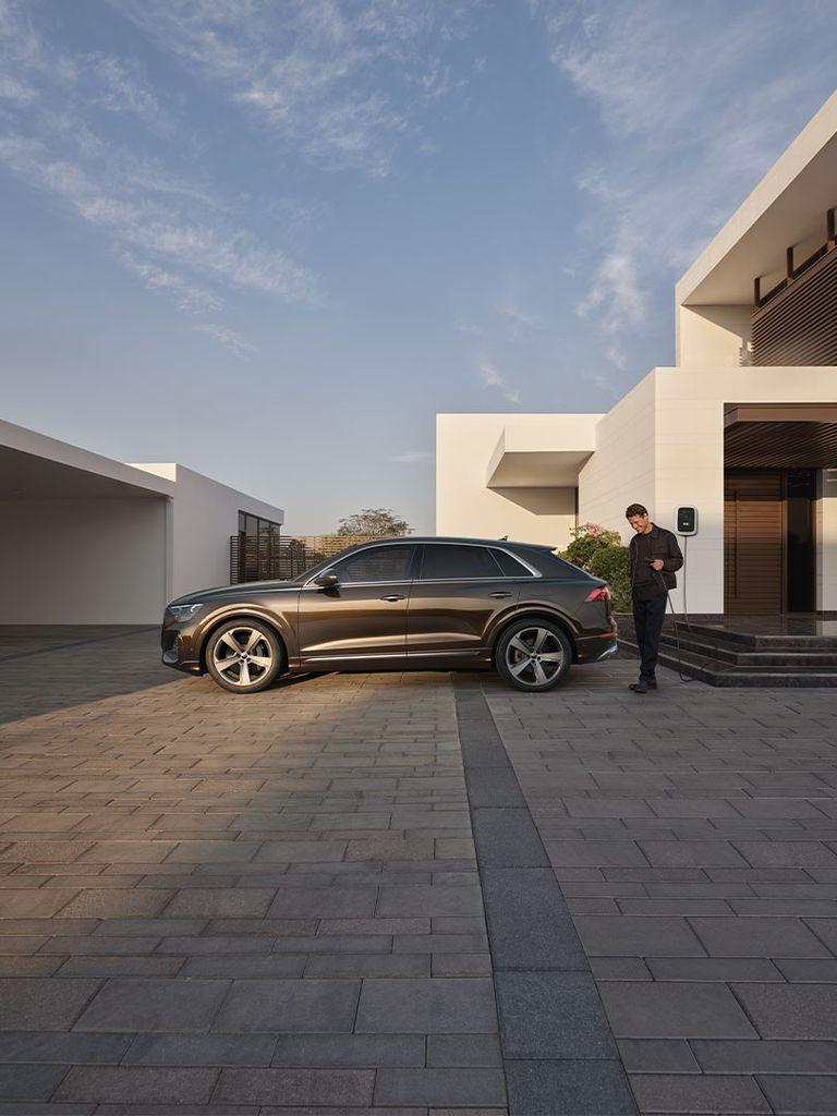 Man charging his Audi Q8 SUV TFSI e at home
